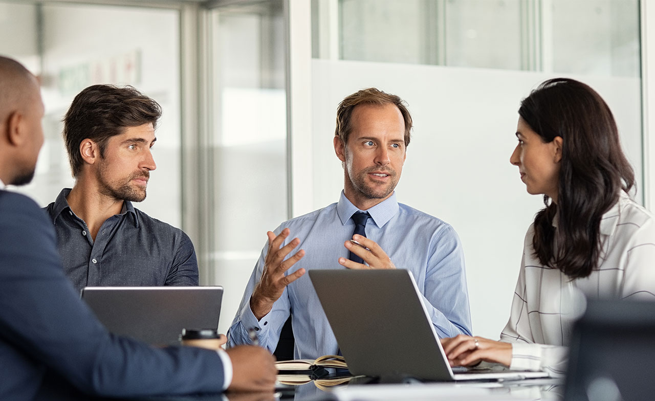 Consultants having a discussion in an office with laptops