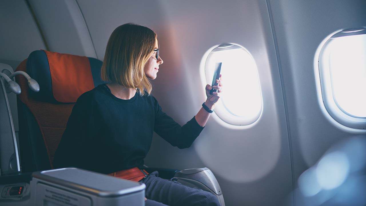 Business woman taking photo on smartphone while sitting in airplane
