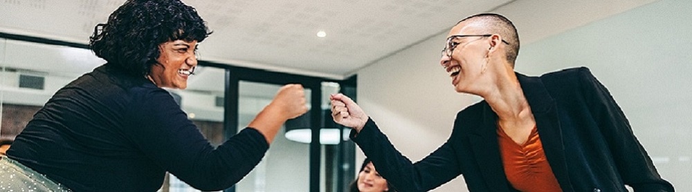 Colleagues fist pumping over a conference table