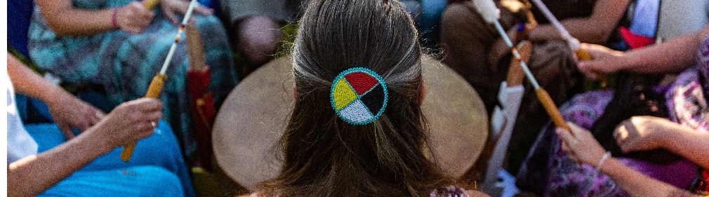 native american woman with back to camera leads drum circle