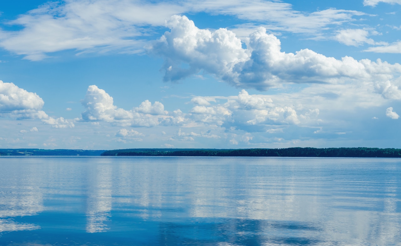 Kama River, darüber blauer Himmel mit Wolken, die sich im Wasser spiegeln