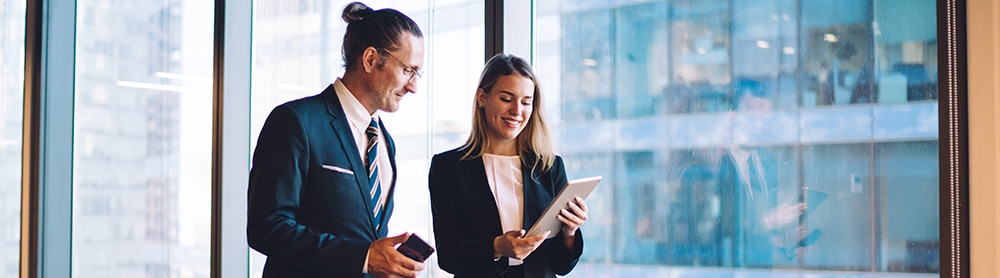 Male and female office worker looking at a tablet computer and smiling
