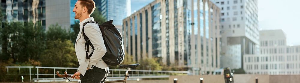 Person walking alongside bicycle in cityscape 