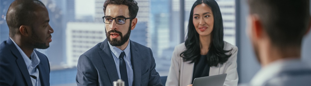  four consultants sit in discussion around an office table