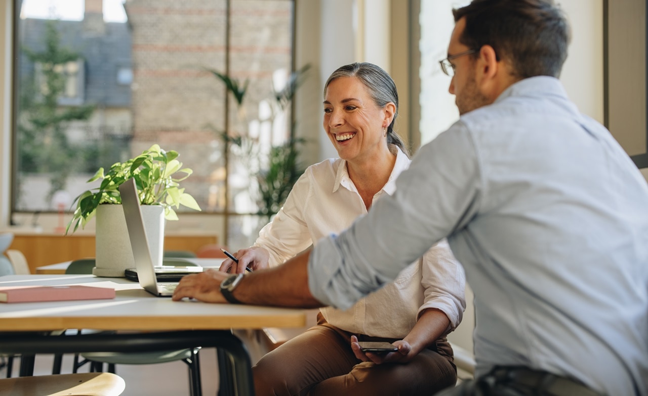 A man and a woman looking at a computer
