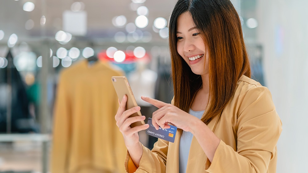 Woman with phone smiling in retail store