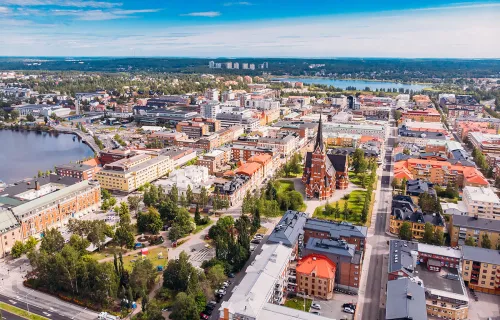 Flygfoto över en svensk stad under sommaren med tydlig stadsstruktur, parker, kyrka i centrum…