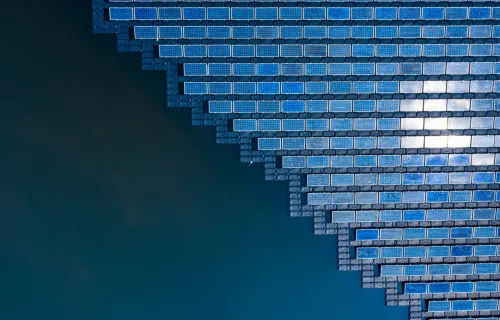 Aerial view of floating solar panels arranged in a geometric pattern on a body of water