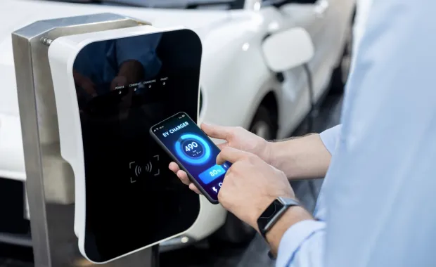 person holding mobile device to EV charging station