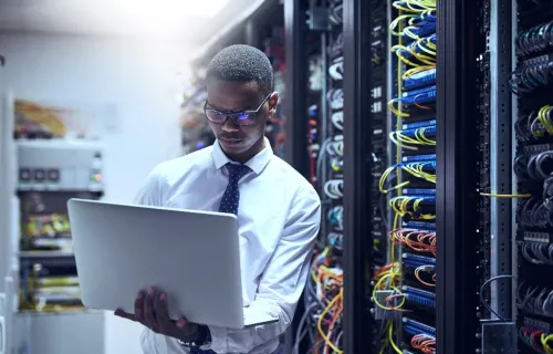 Cloud-Experte steht mit seinem Laptop in der Hand in einem Rechenzentrum