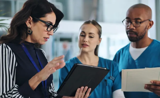 consultant discussing data on a tablet with healthcare professionals