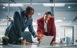 two executives pointing to laptop discussing cybersecurity and risk management