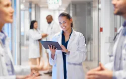 docor using tablet in hospital hallway