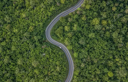 Aerial view of a road weaving through forest surroundings