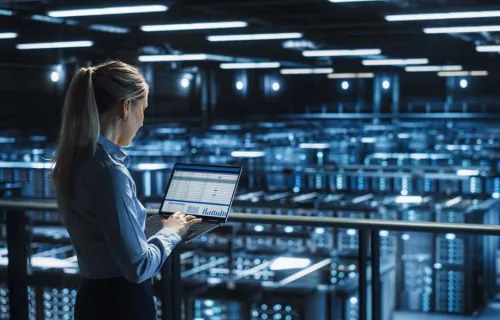 Frau steht mit Laptop in einem Rechenzentrum