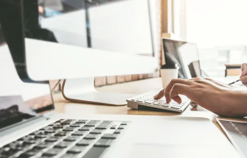 Une main de femme en train d'écrire sur un clavier d'ordinateur