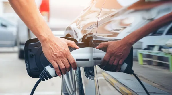 Person holding electric charger into car charging port