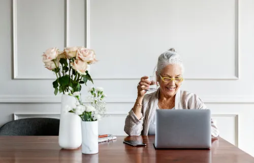 Person sitting at desk with flowers looking at laptop