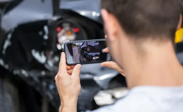 person takes picture of damaged car for insurance claim