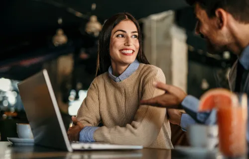 Two professionals talking in front of laptop