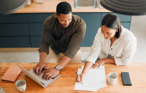 Zwei Personen stehen an einem Schreibtisch und arbeiten