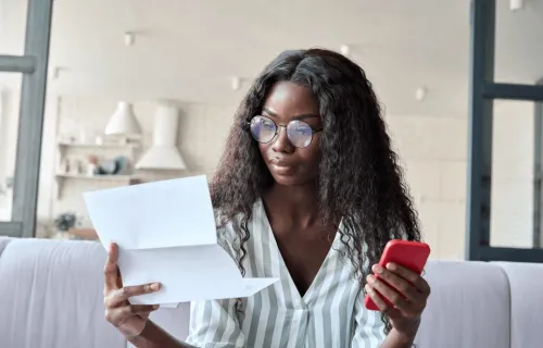 Women looking at paper holding phone